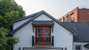 A residential house with a white exterior, a red front door, a small balcony with black railings, and a garage door. - Easy access to Taylor Swift, Broadway, CMAs & more (Nashville)