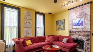 A living room with a red sofa, a round coffee table, and a brick fireplace. - Easy access to Taylor Swift, Broadway, CMAs & more (Nashville)