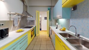 Eine moderne Küche mit gelben und türkisblauen Schränken, Edelstahlgeräten und einer gefliesten Spritzschutzwand.