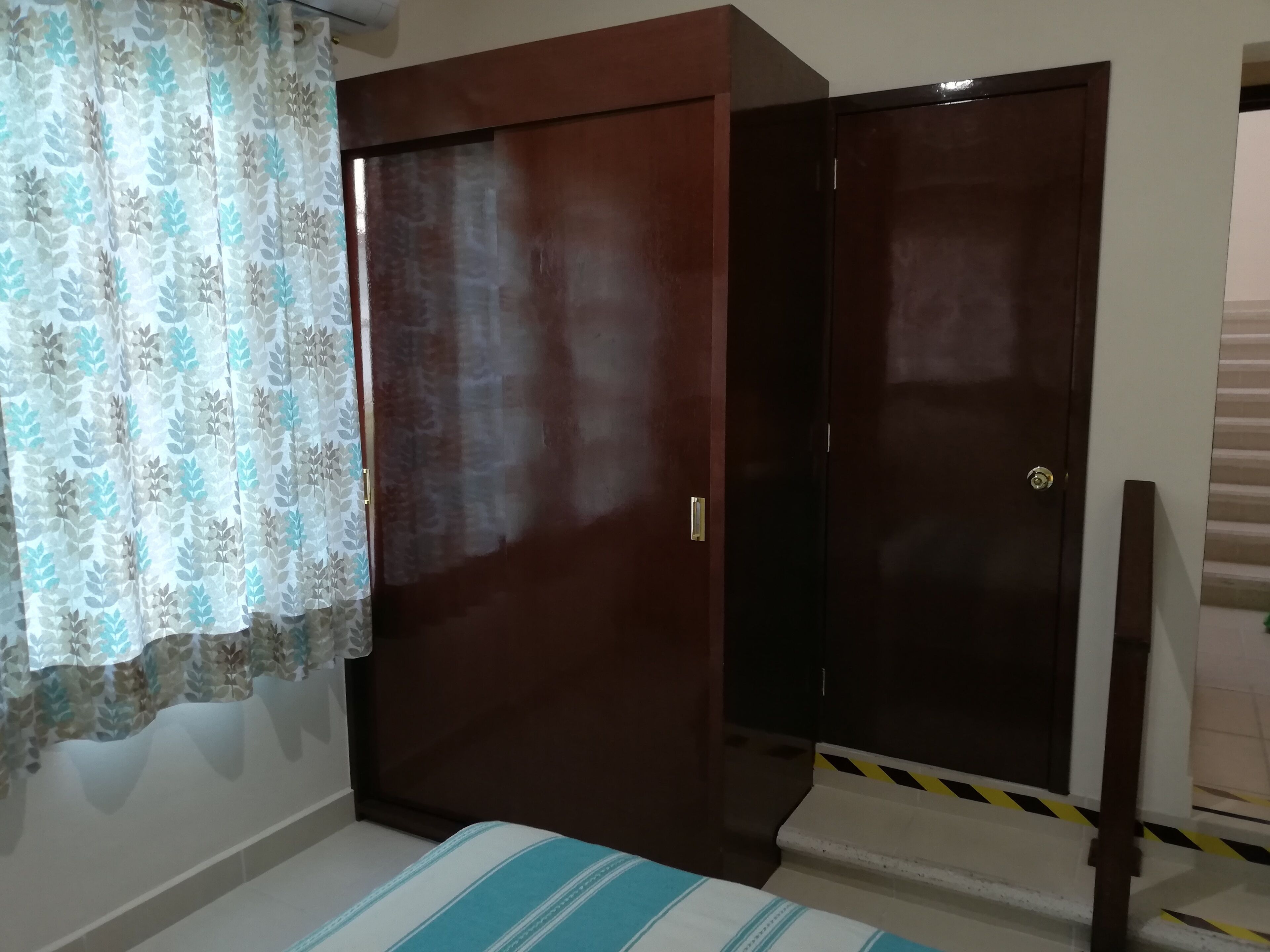 Une chambre à coucher avec un lit, une armoire et un rideau.