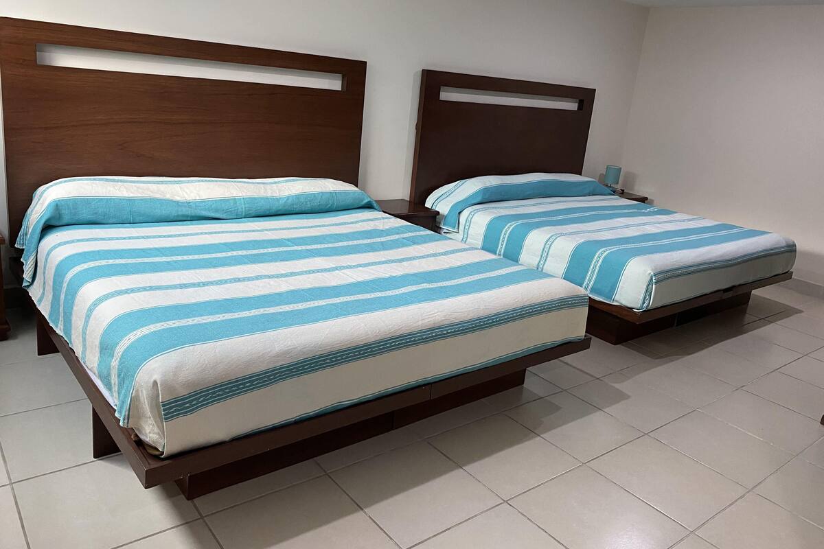 A hotel room with two beds, each with a wooden headboard and a striped bedspread.