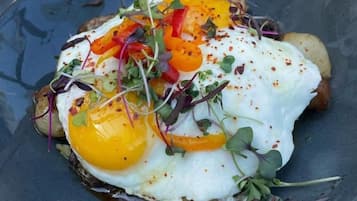 Un plato con un huevo estrellado, pimientos y vegetales verdes.