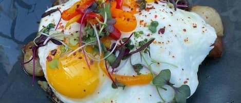 Un plato con un huevo estrellado, pimientos y vegetales verdes.
