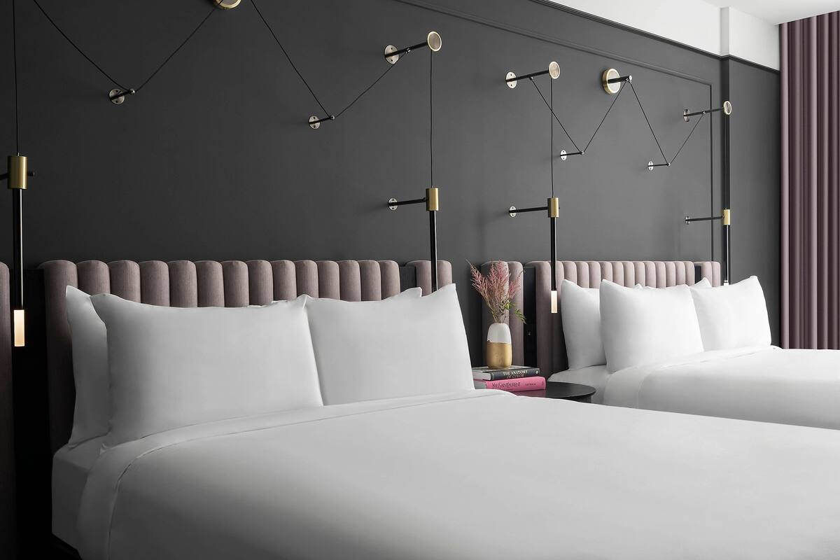 A modern hotel room with a large bed, a bedside table, and a wall-mounted light fixture.