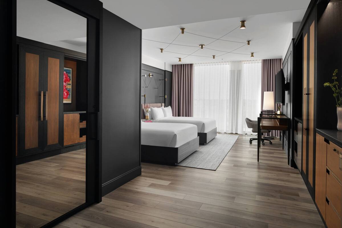 A modern hotel room with a large bed, a desk, and a TV.