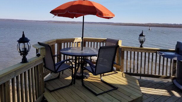 A wooden deck with a table and chairs, an umbrella, and two lanterns. - River Life at it's Best (Chillicothe)