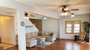A spacious living room with a sectional sofa, wooden flooring, ceiling fans, and a large window with a view. - River Life at it's Best (Chillicothe)