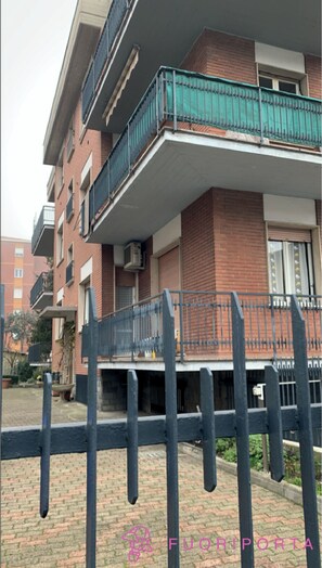 Residential building with a flat roof and balconies on each floor, offering an outdoor space.