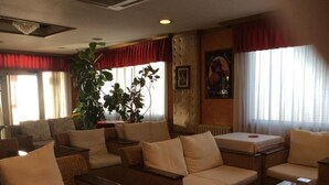 A hotel lobby with wicker sofas, a coffee table, and a large plant. - Hotel Internacional (O Porrino)