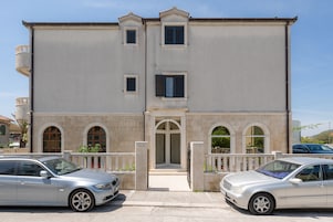 A two-story building with a central entrance, a balcony, and a gated driveway.
