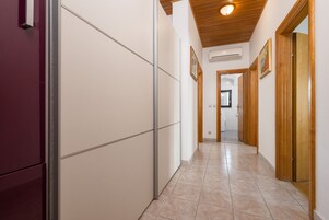 Un couloir doté d’un sol carrelé, de portes en bois et d’un plafond avec un luminaire.