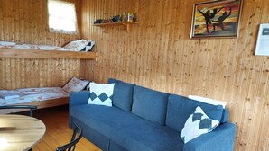 Una habitación acogedora con un sofá azul, una cama litera de madera y una mesita pequeña.