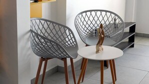Twee grijze stoelen met houten poten en een witte tafel in een moderne kamer met betegelde vloer.