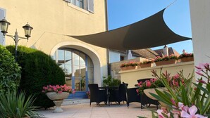 Un patio al aire libre con suelo de piedra, una mesa y sillas, y plantas en macetas.