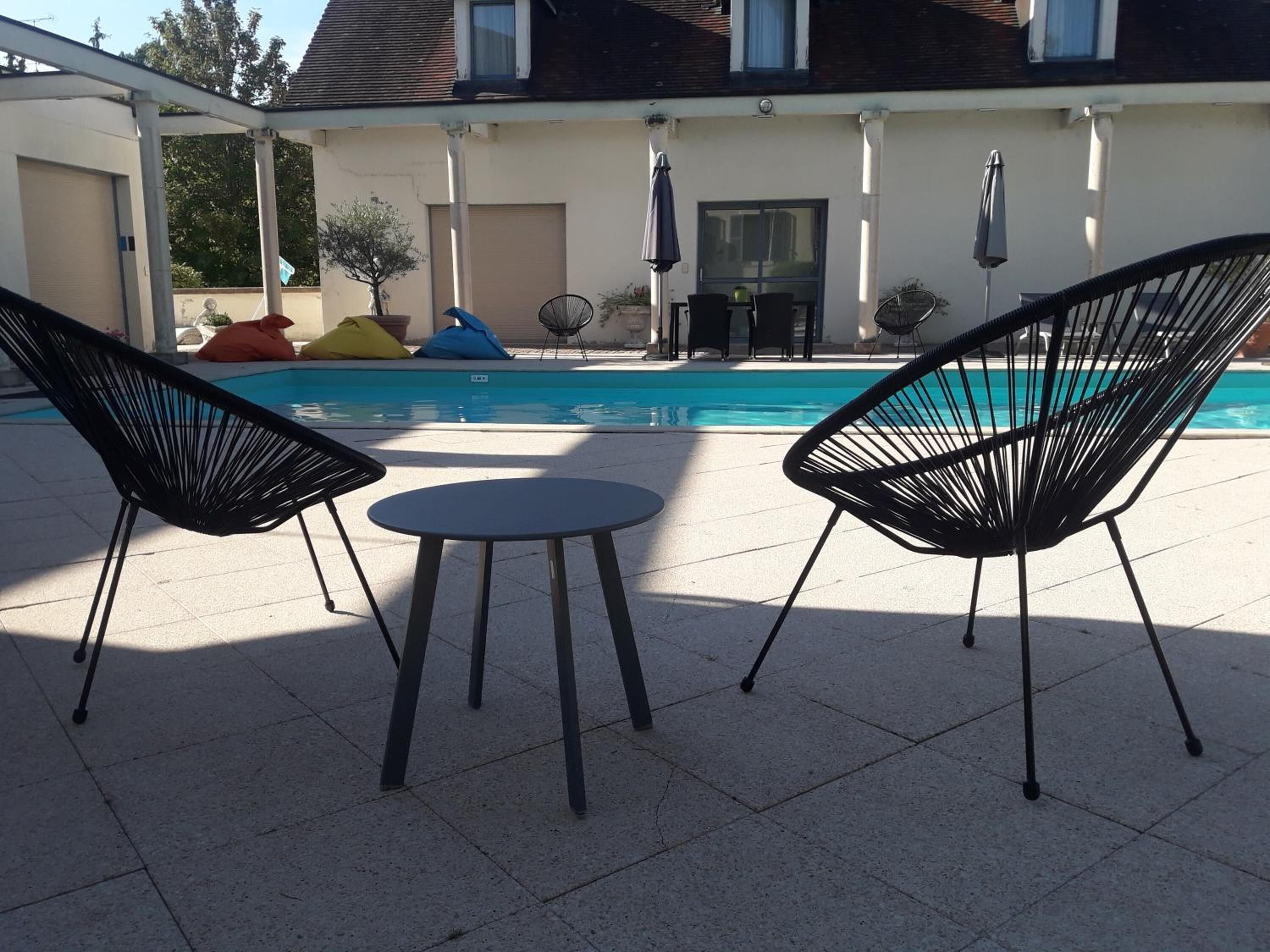 A poolside area with two black chairs and a small table.