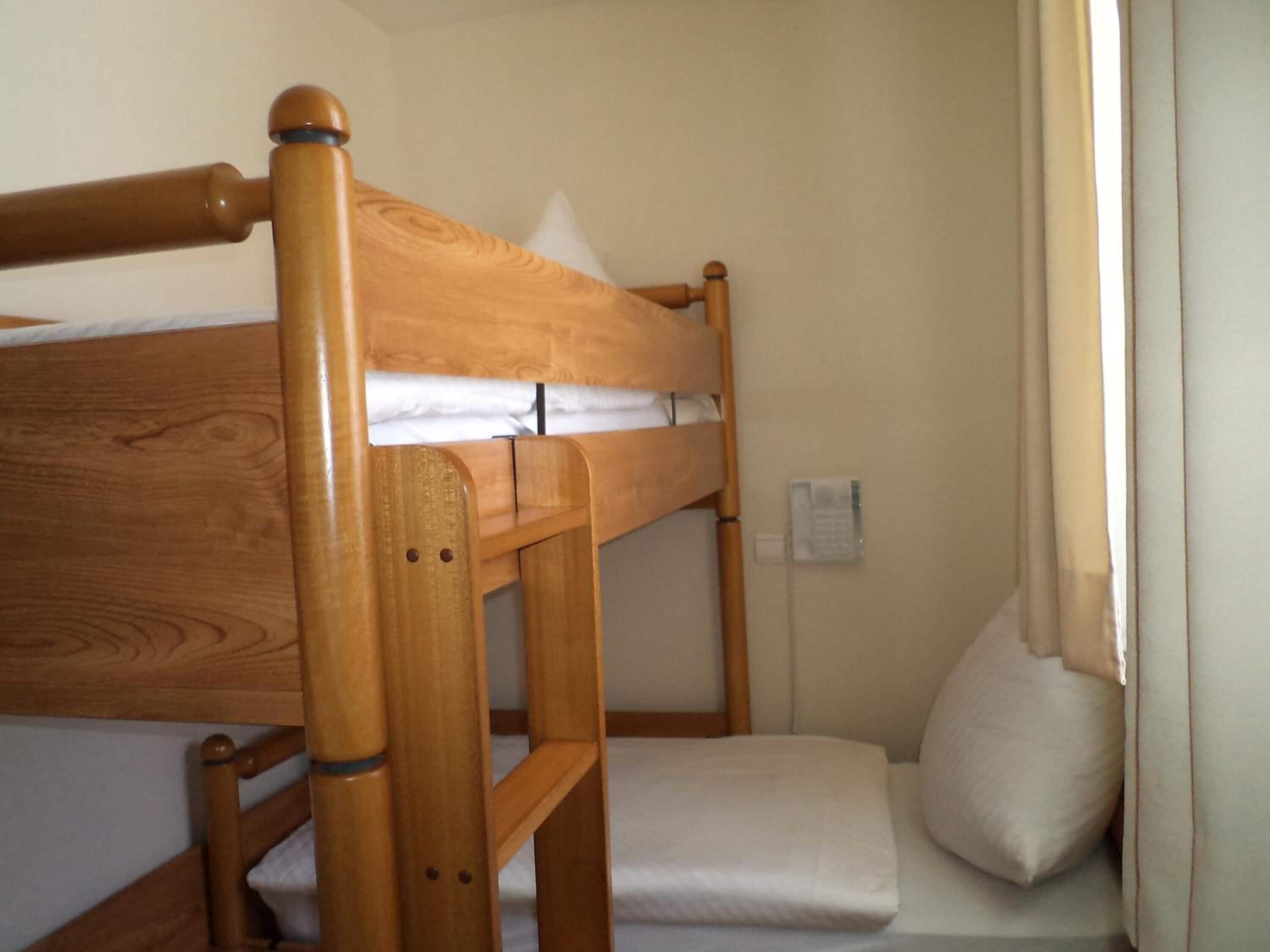 A bunk bed with a wooden frame and white bedding.
