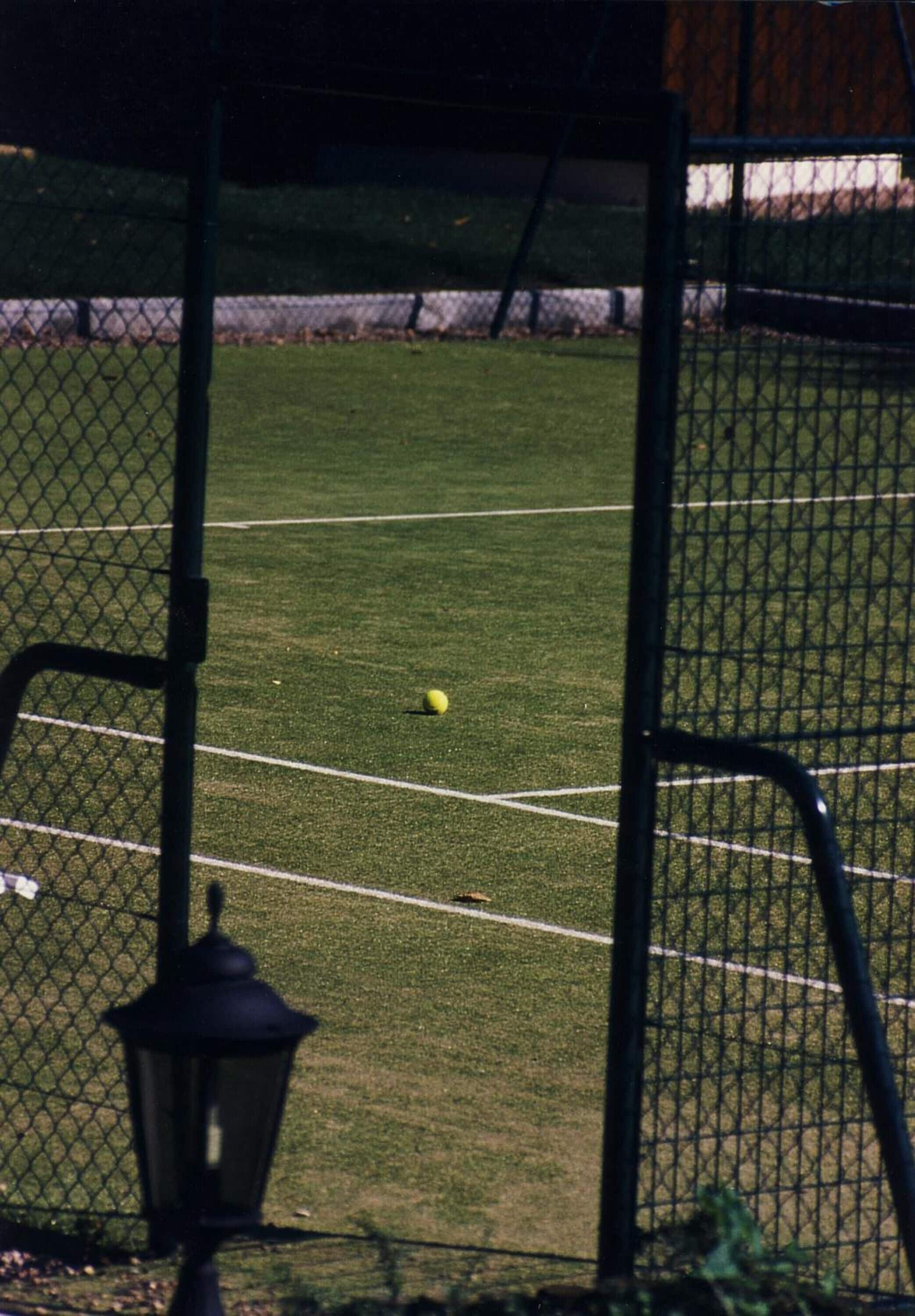 Ein Tennisplatz mit Netz und Laterne im Vordergrund.
