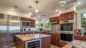 A modern kitchen with stainless steel appliances, wooden cabinets, and a central island. - 9 Bedroom Oceanfront Beach House in Debordieu (Georgetown)