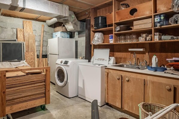 A laundry room with a washing machine, dryer, and a cart with wooden planks. - 9 Bedroom Oceanfront Beach House in Debordieu (Georgetown)