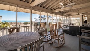A covered outdoor dining area with wooden furniture and a view of the beach and ocean. - 9 Bedroom Oceanfront Beach House in Debordieu (Georgetown)