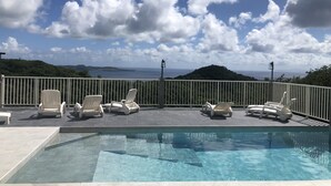 Ein Poolbereich mit Liegestühlen und Blick auf den Ozean.