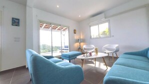 Ein modernes Wohnzimmer mit blauen Sofas, einem kleinen runden Tisch und einem Balkon mit Blick.