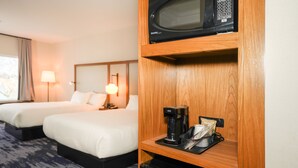 Une chambre d’hôtel avec deux lits, un four à micro-ondes, une machine à café et une poubelle.