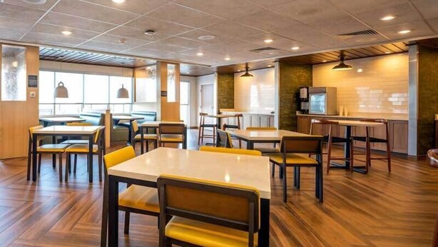 Un espace de restauration moderne avec un plancher en bois, des tables et des chaises jaunes.