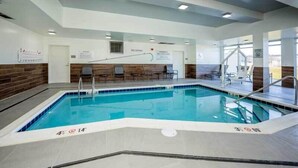 Une piscine intérieure avec des lignes de démarcation bien visibles, un mur en bois et un espace détente avec des chaises.