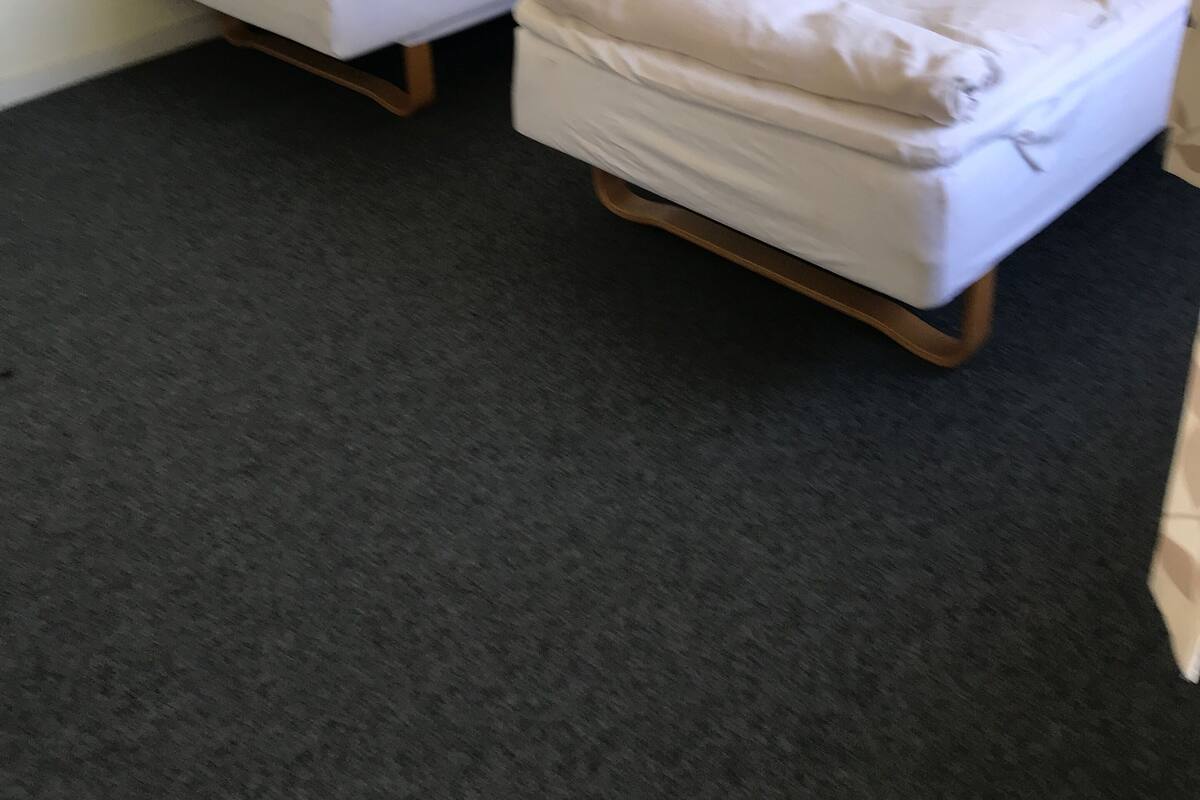 A room with two single beds, a small bedside table, and a wall-mounted light fixture.