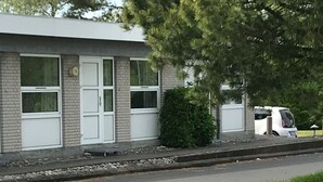 A building with a brick facade, white doors, and windows. There is a white car parked in front. - Motel Hadsten (Hadsten)