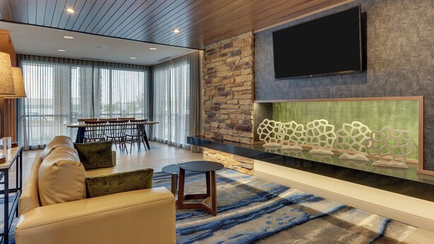 A modern living room with a stone wall, a flat-screen TV, a fireplace, and a sofa. - Fairfield Inn & Suites by Marriott Warsaw (Warsaw)