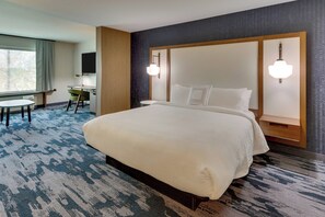 A hotel room with a large bed, a desk, a chair, and a television.