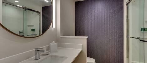 Un baño moderno con un espejo grande, un lavabo y un inodoro.