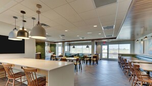 A spacious dining area with multiple tables and chairs, a long counter, and pendant lighting. - Fairfield Inn & Suites by Marriott Warsaw (Warsaw)