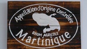 Une enseigne en bois représentant en silhouette blanche un taureau, avec l’inscription « Appellation d’Origine Contrôlée Martinique ».