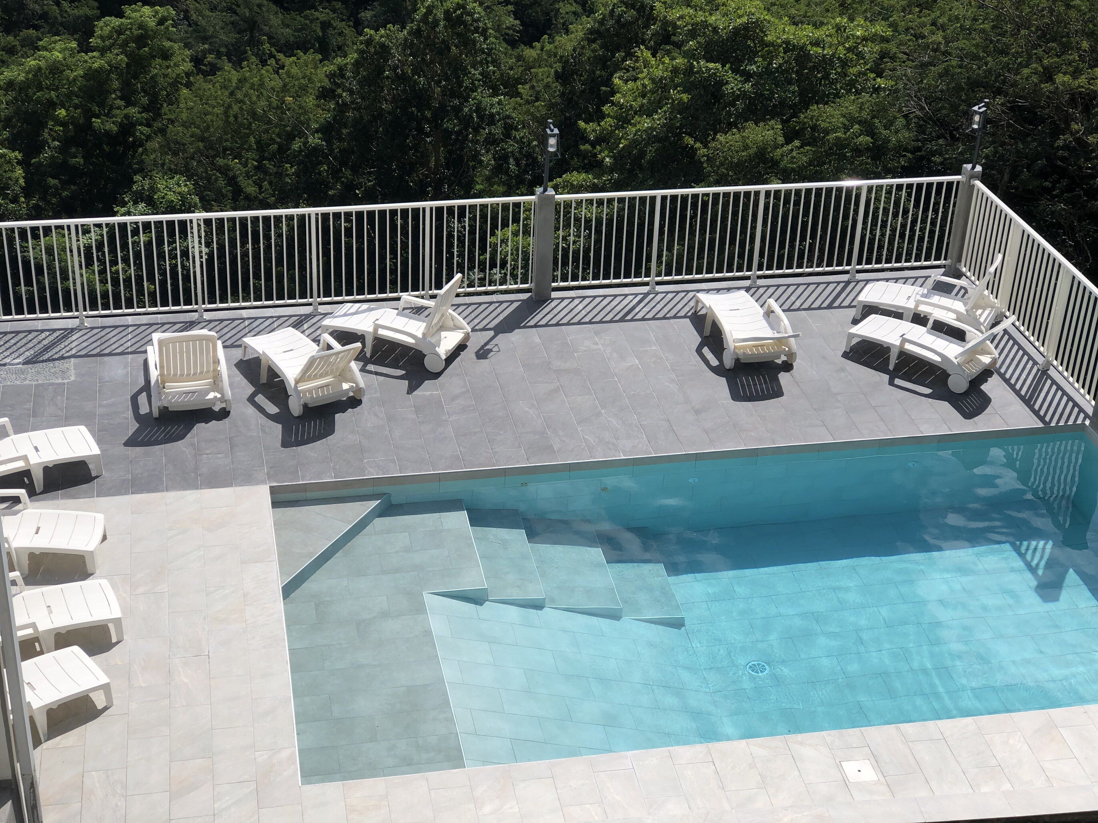 A rooftop pool area with multiple lounge chairs and a swimming pool.