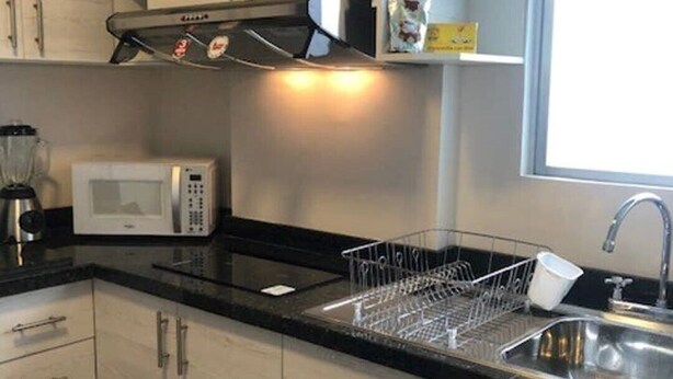 A modern kitchen with light-colored cabinets, a microwave, a coffee maker, and a dish rack. - Suite location and comfort in Quito Hi speed wifi (Quito)