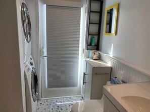 Een kleine badkamer met een geïntegreerde wasmachine, toilet en wastafel.