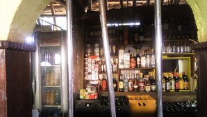 A bar area with shelves stocked with various bottles and a refrigerator with beverages. - Camp David (Makindu)