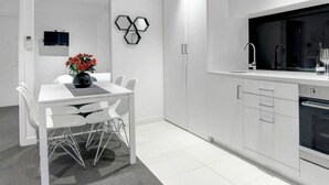 A modern kitchen with white cabinetry, a dining area with a white table and chairs, and a small decorative wall piece.