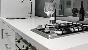 A modern kitchen with a gas stove, a sink, and wine glasses.