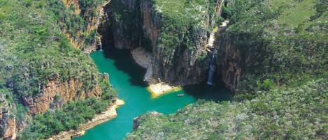 A canyon with a river, cliffs, and a waterfall.