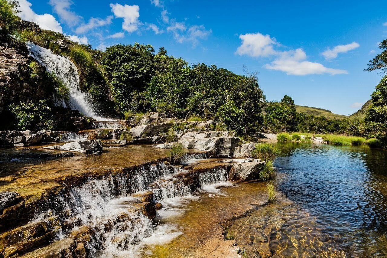 A natural landscape with a waterfall, clear water, and surrounding greenery.