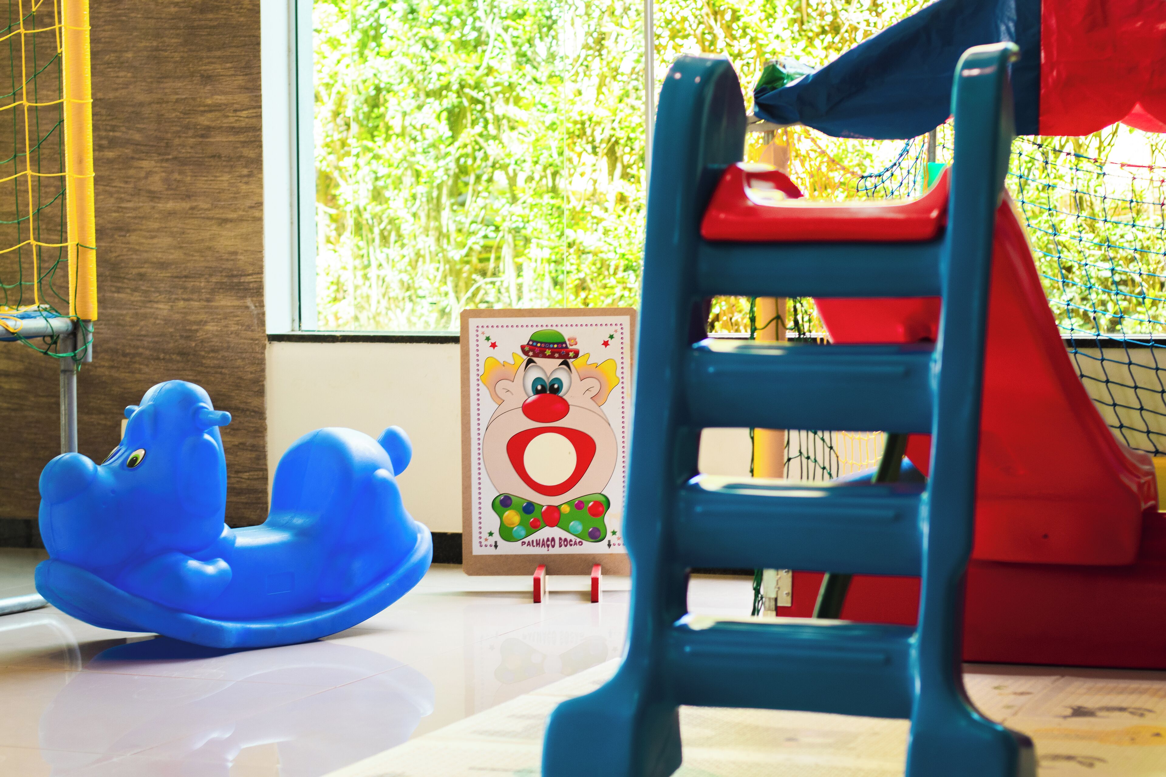 A blue toy on a table, a red and blue chair, and a poster with a cartoon character.
