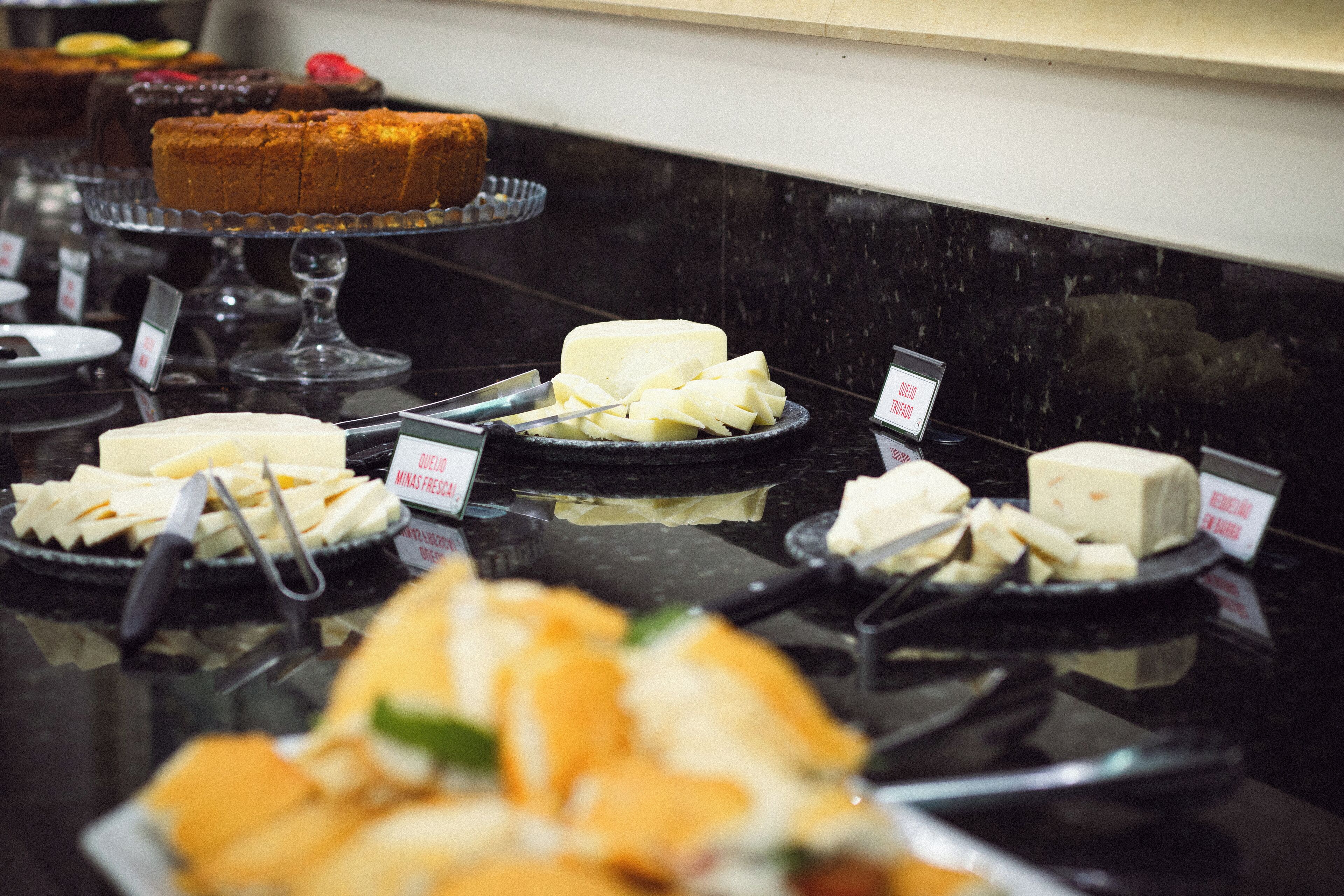 A buffet with various cheeses and a cake on display.