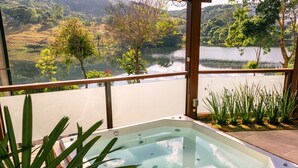 Un jacuzzi con vistas a un lago y follaje circundante.