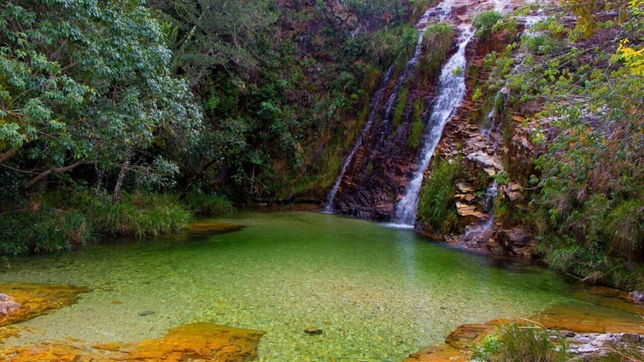 A natural waterfall with clear water and surrounding greenery.