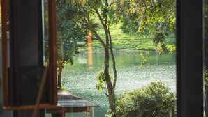 Una mesa de billar con bolas, vista al lago por la ventana y un caballete de pintura.