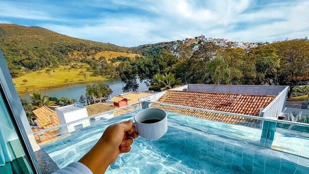 Una persona relajándose junto a una piscina con vistas a una colina y un pueblo lejano.